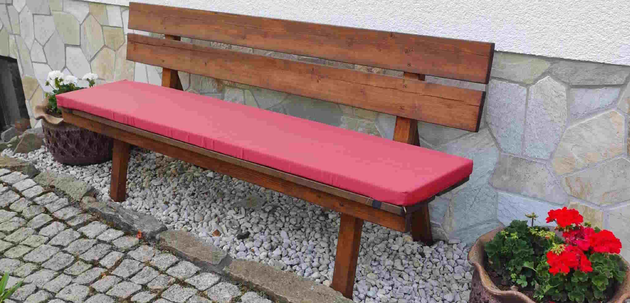 große Bank mit rotem Sitzkissen, an Haus stehend